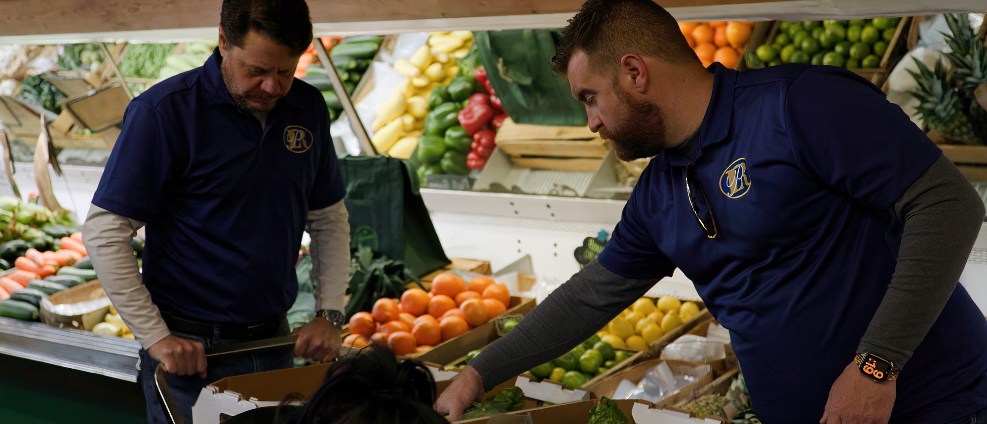 Two men packing boxes with fresh produce